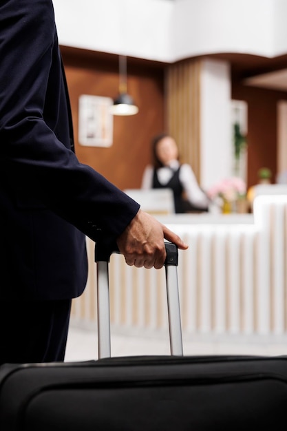 Foto grátis hóspede do hotel entrando na recepção com bagagem, viajando para o exterior para participar de importantes reuniões de negócios. empresário abordando a recepção para check-in, reserva de acomodação. fechar-se.