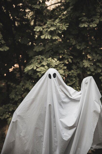 Humano em traje de fantasma com as mãos levantadas