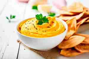 Foto grátis hummus de abóbora em tigela com pão pita na mesa de madeira branca