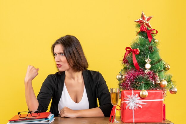 Humor de Natal com jovem empresária estressada emocionalmente, sentada a uma mesa no escritório