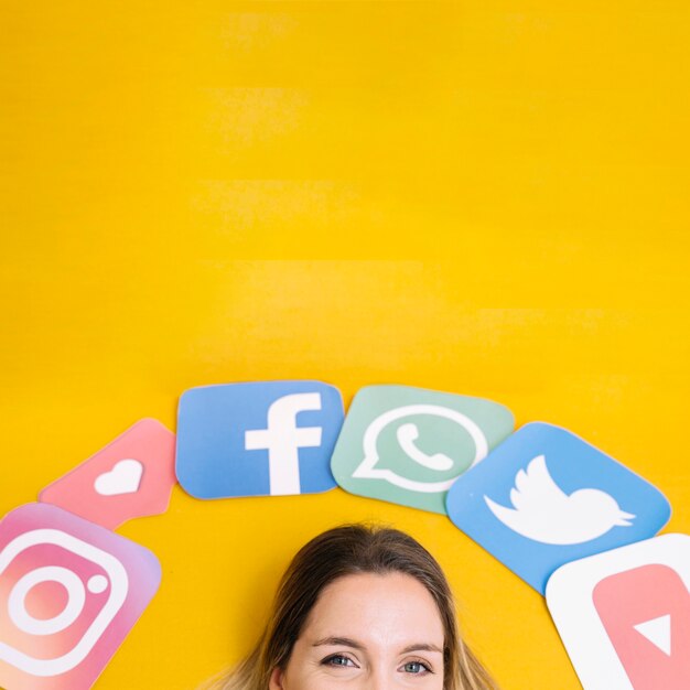 Ícones de aplicativos de mídia social sobre a cabeça da mulher em pano de fundo amarelo