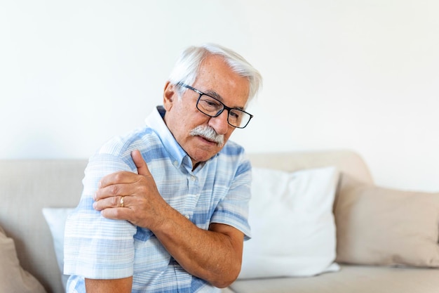 Foto grátis idoso idoso com dor no ombro idoso sênior chateado sente dor súbita nos músculos dor de tensão lesão em casa avô tocando ombro com osteoartrite artrite