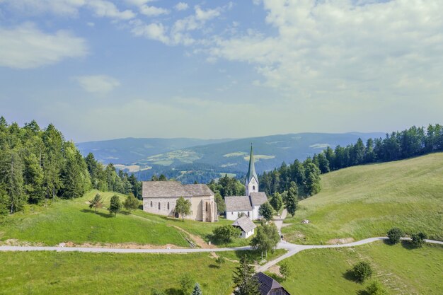 Igreja de Lese em um campo cercado por colinas cobertas de vegetação na Eslovênia