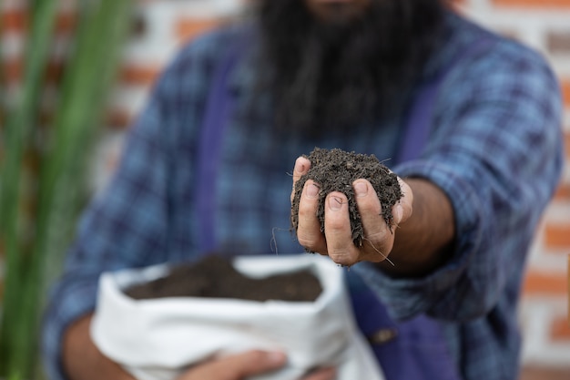 Imagem aproximada das mãos de jardineiro segurando o solo