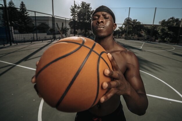 Imagem aproximada de um jogador de basquete negro em um pátio externo