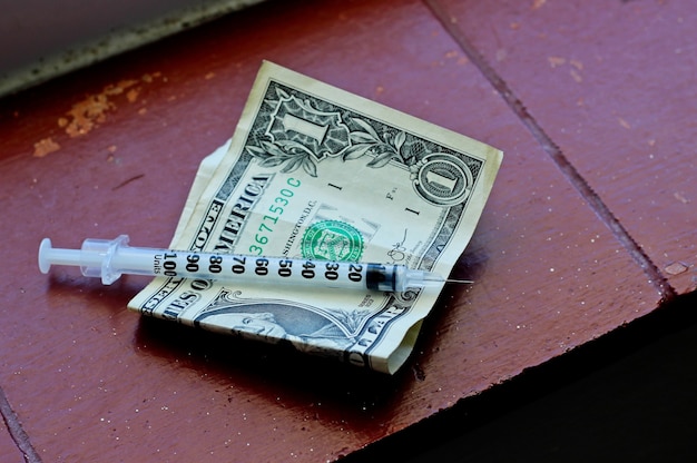 Imagem aproximada de uma agulha em uma nota de um dólar em uma superfície marrom
