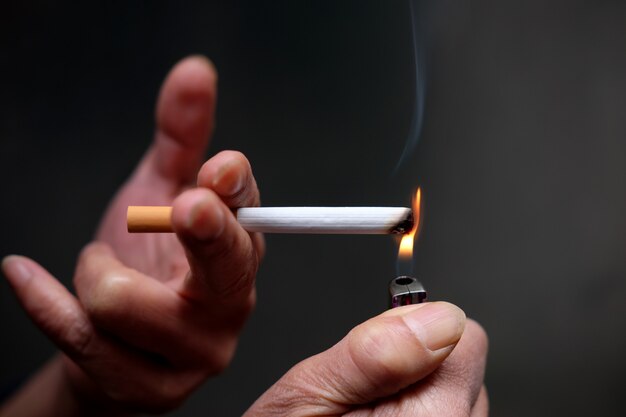 Imagem aproximada de uma pessoa acendendo um cigarro