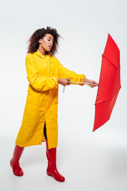 Imagem completa de mulher africana confusa no guarda-chuva de abertura da capa de chuva