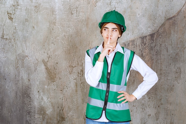 Imagem da bela arquiteta com um capacete verde em pé sobre o mármore