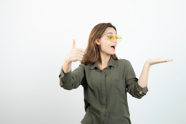 Imagem de adorável garota de óculos dando polegares para cima sobre branco. foto de alta qualidade