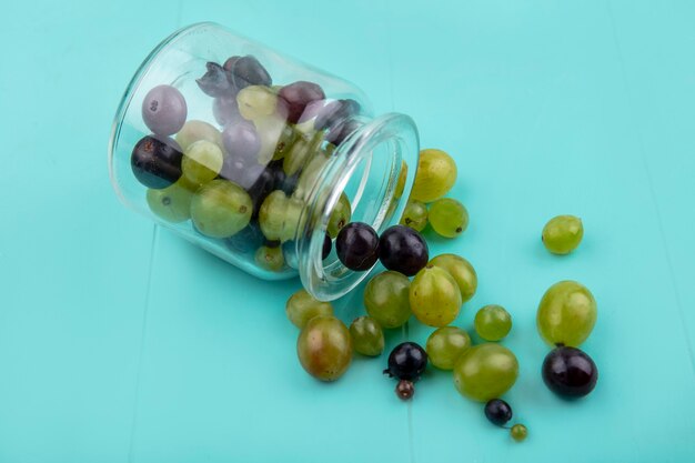 Imagem de close-up de bagos de uva caindo da jarra sobre fundo azul
