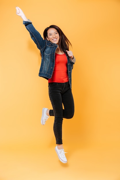 Imagem de corpo inteiro de alegre mulher asiática na jaqueta jeans
