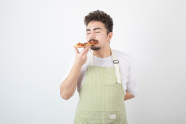 Imagem de cozinheiro masculino comendo uma fatia de pizza em branco