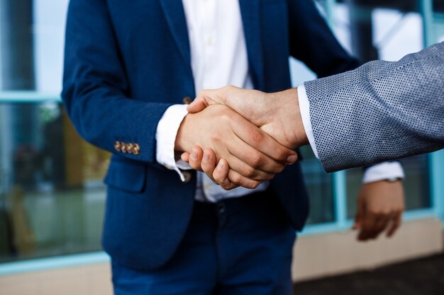 Imagem de dois jovens empresários na rua, apertando as mãos