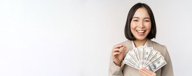 Imagem de empresária bem-sucedida segurando dinheiro Mulher corporativa asiática com dólares em dinheiro sorrindo e rindo em pé sobre fundo branco