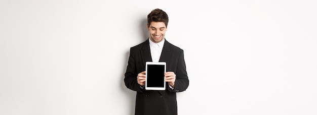 Foto grátis imagem de empresário bonito de terno preto olhando para a tela do tablet digital e showi