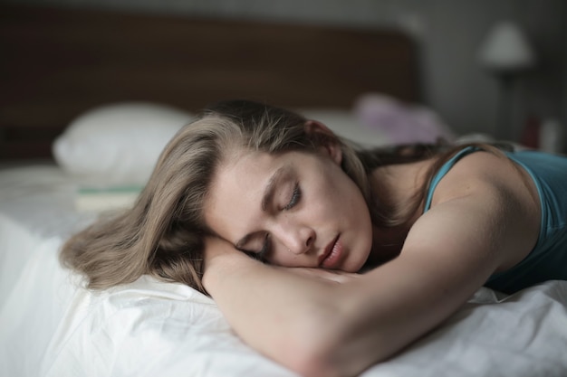 Imagem de foco raso de uma mulher dormindo em sua cama