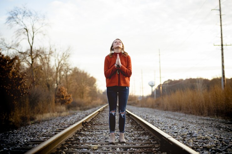 Foto grátis imagem de foco raso de uma mulher em pé nos trilhos do trem enquanto orava