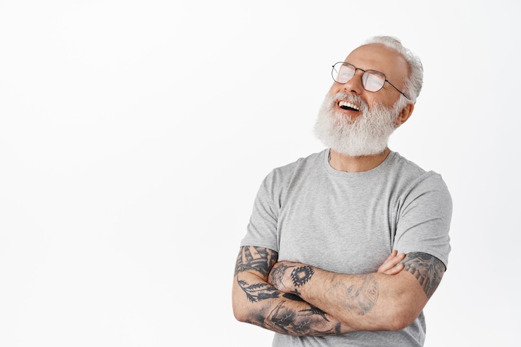 Foto grátis imagem de homem sênior sincero em óculos rindo com os braços cruzados no peito, olhando para o lado com a expressão alegre do rosto relaxado em pé sobre fundo branco