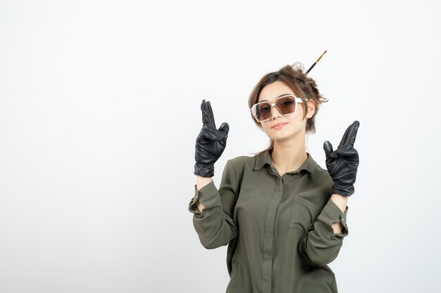 Imagem de jovem adorável de óculos e luvas pretas em pé. Foto de alta qualidade