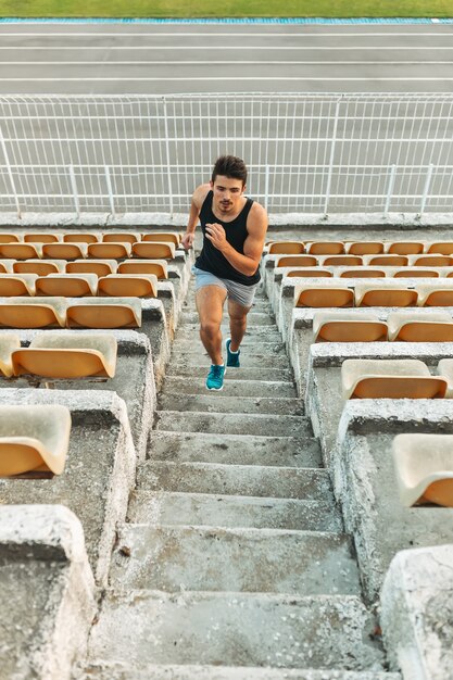 Imagem de jovem atlético correndo pela escada no estádio fora