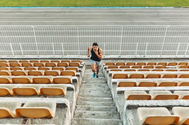 Imagem de jovem atlético correndo pela escada no estádio fora