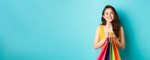 Foto grátis imagem de menina alegre indo às compras segurando sacolas com compras e sorrindo para a câmera em pé aga