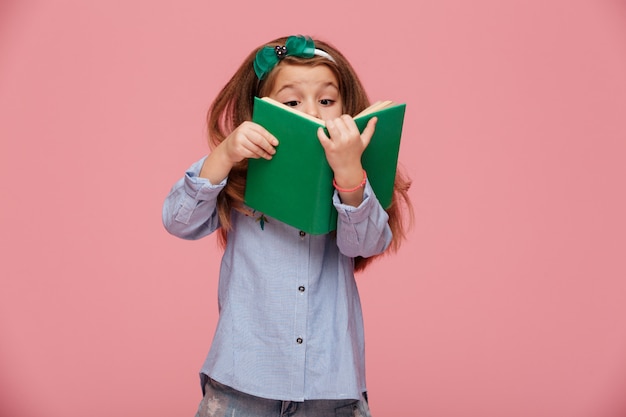 Imagem de menina divertida, com longos cabelos ruivos, lendo um livro interessante se divertindo