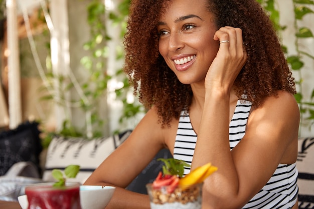 Imagem de mulher negra sentada de lado com expressão alegre