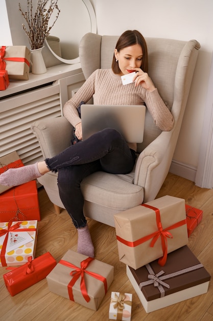 Imagem de mulher simpática e satisfeita segurando um cartão de crédito com espaço de cópia usando um laptop