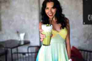 Foto grátis imagem de nutrição de uma jovem mulher bonita com vestido de verão mostrando bebida verde, saborosa e saudável.