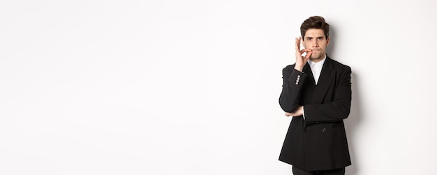 Imagem de um empresário sério de terno preto fechando a boca e franzindo a testa escondendo segredo mostrando tabu si
