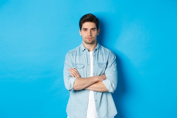 Foto grátis imagem de um homem bonito, caucasiano, em roupa casual, parecendo sério e confiante, em pé contra um fundo azul