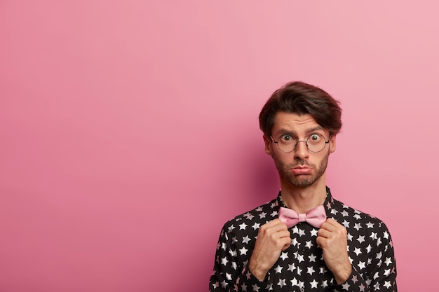 Imagem de um homem com a barba por fazer surpreso ajustando a gravata borboleta e se preparando para uma reunião importante