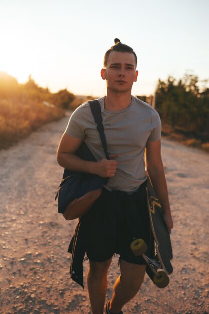 Imagem de um homem com longboard indo na estrada