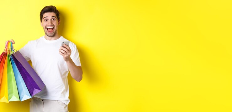 Foto grátis imagem de um homem feliz recebendo dinheiro de volta pela compra segurando smartphone e sacolas de compras sorrindo excitante