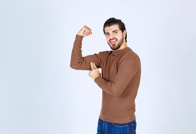 Imagem de um jovem bonito de pé e mostrando seus músculos. Foto de alta qualidade