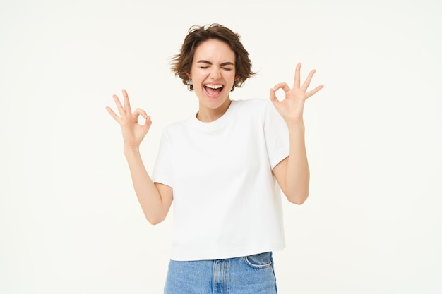 Foto grátis imagem de uma garota feliz e sorridente mostra um sinal de ok, recomendando curtir e aprovar algo de boa reputação