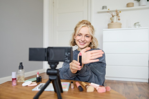 Foto grátis imagem de uma jovem criadora de conteúdo, blogueira de beleza, sentada no chão de seu quarto, gravando um vídeo sobre