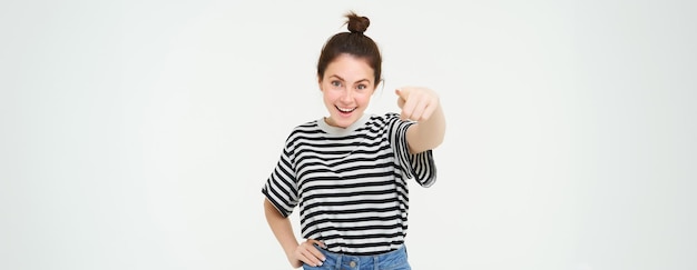Foto grátis imagem de uma jovem feliz e confiante em roupas casuais apontando o dedo para a câmera rindo e