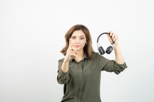 Imagem de uma jovem mulher atraente segurando fones de ouvido pretos. foto de alta qualidade
