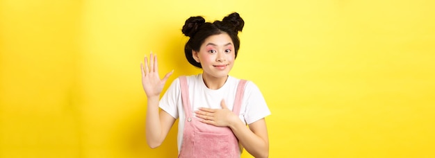 Foto grátis imagem de uma linda garota asiática com maquiagem sendo honesta levantando a mão e colocando o coração dizendo a verdade