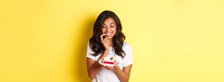 Foto grátis imagem de uma linda mulher africana-americana olhando com um sorriso tentado para um delicioso pedaço de bolo