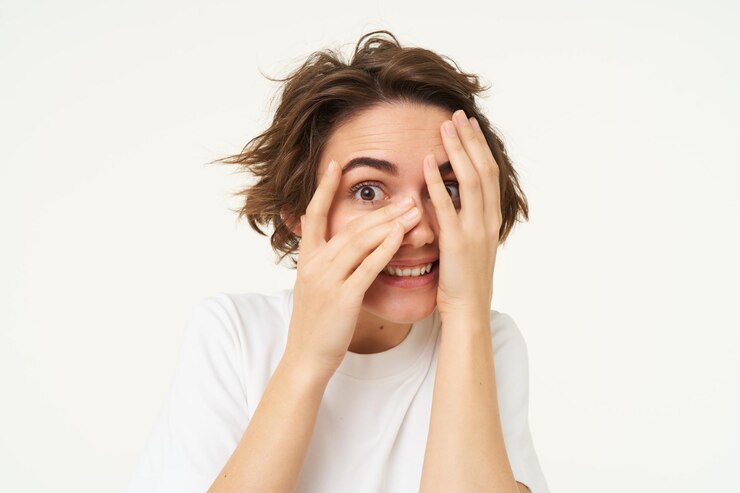 Foto grátis imagem de uma mulher engraçada espiando por entre os dedos olhando para algo com uma expressão curiosa