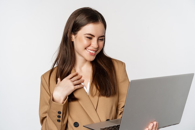 Foto grátis imagem de uma videochamada de empresária sorridente no laptop rindo enquanto olha para o computador em pé novamente...