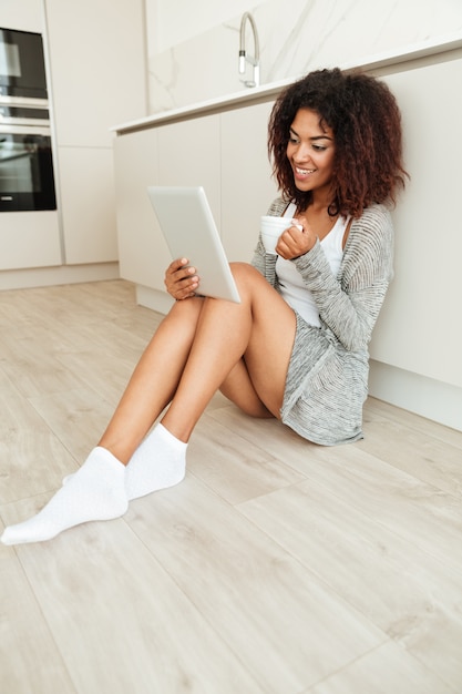 Imagem de Vertica da mulher africana sorridente, sentada no chão