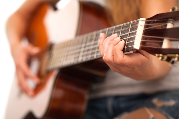 Imagem do close up da guitarra nas mãos da mulher