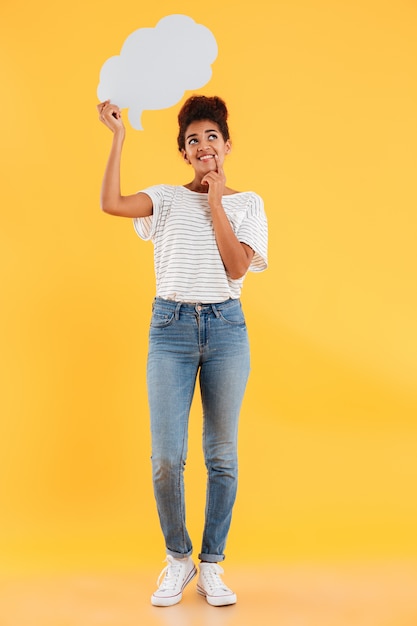 Imagem do comprimento total da mulher africana pensativa sorridente, olhando para cima