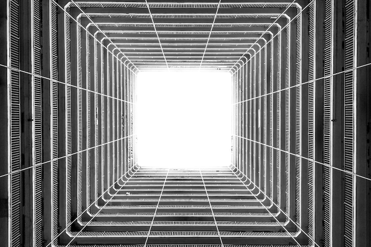 Foto grátis imagem em tons de cinza de baixo ângulo da luz entrando pelo teto de um prédio alto