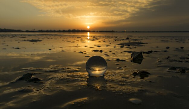 Imagem hipnotizante de uma pequena bola transparente na praia capturada durante o pôr do sol